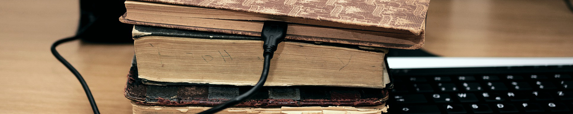 old books with charging cord coming out it next to computer keyboard